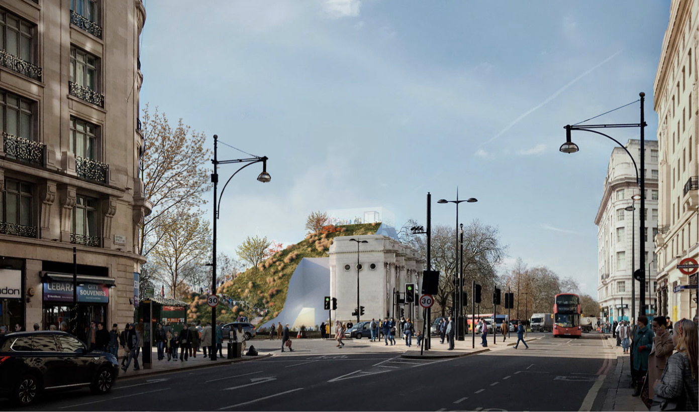View of Marble Arch Mound from Oxford Street, with buildings, main road, double decker bus, people and blue sky