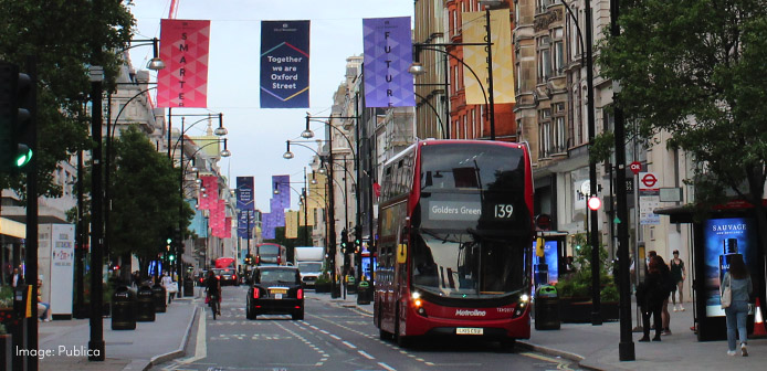 Double decker bus on Oxford Street, with trees and banners above the street